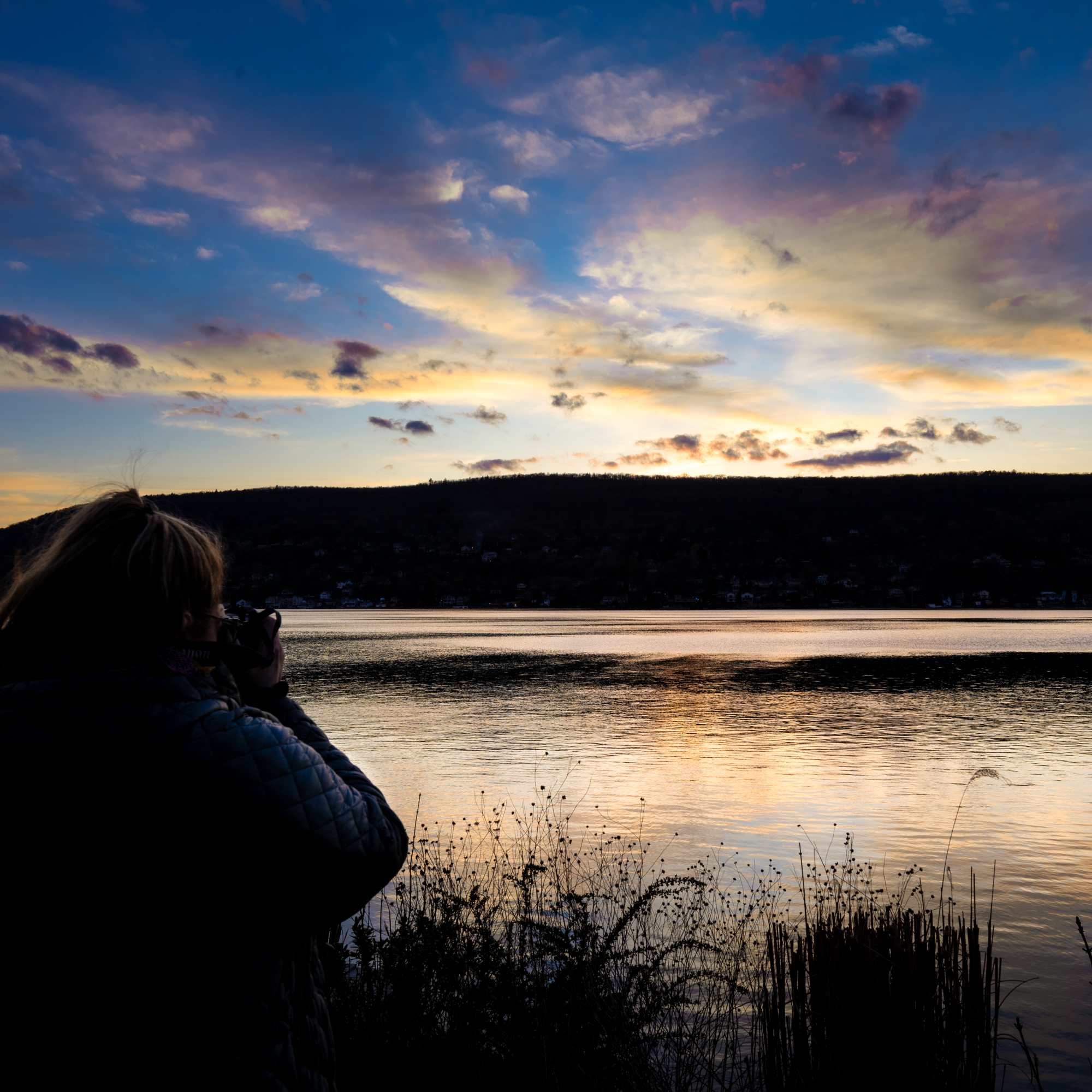 She's snapping a  magical sunset at the lake 